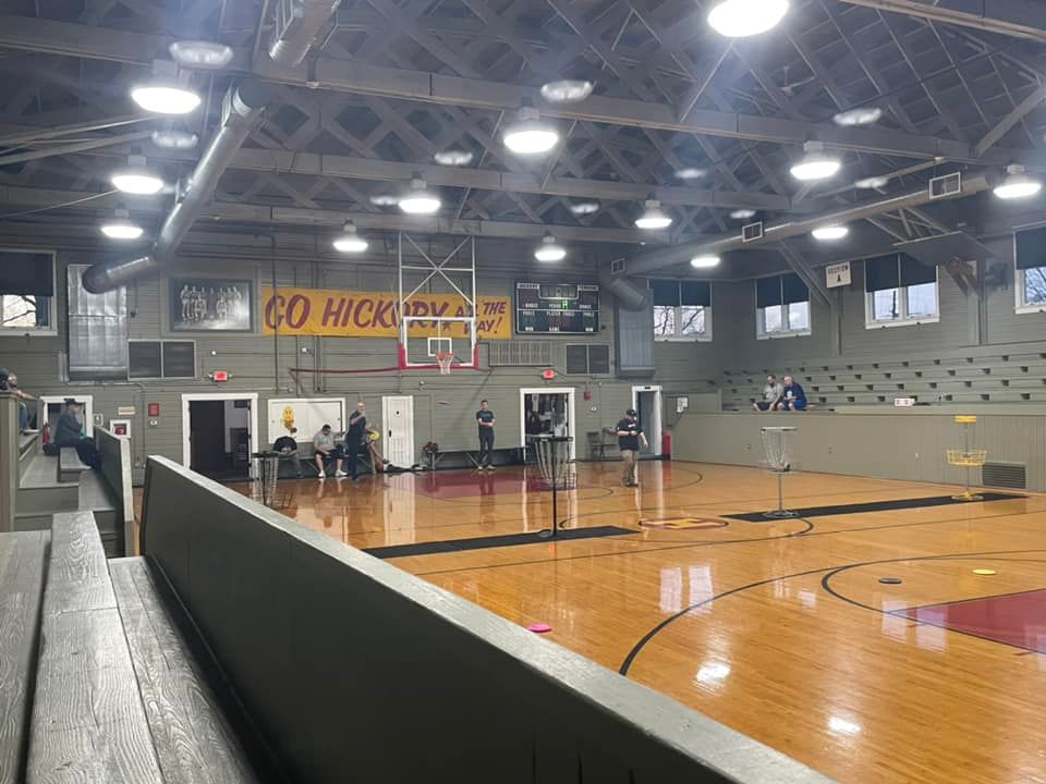 Image of an indoor disc golf course at The Hoosier Gym. Players are waiting to throw their discs.